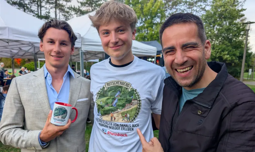 Daniel Phiesel lacht mit zwei jungen Männern, einer trägt ein Rutschenberg-Shirt.